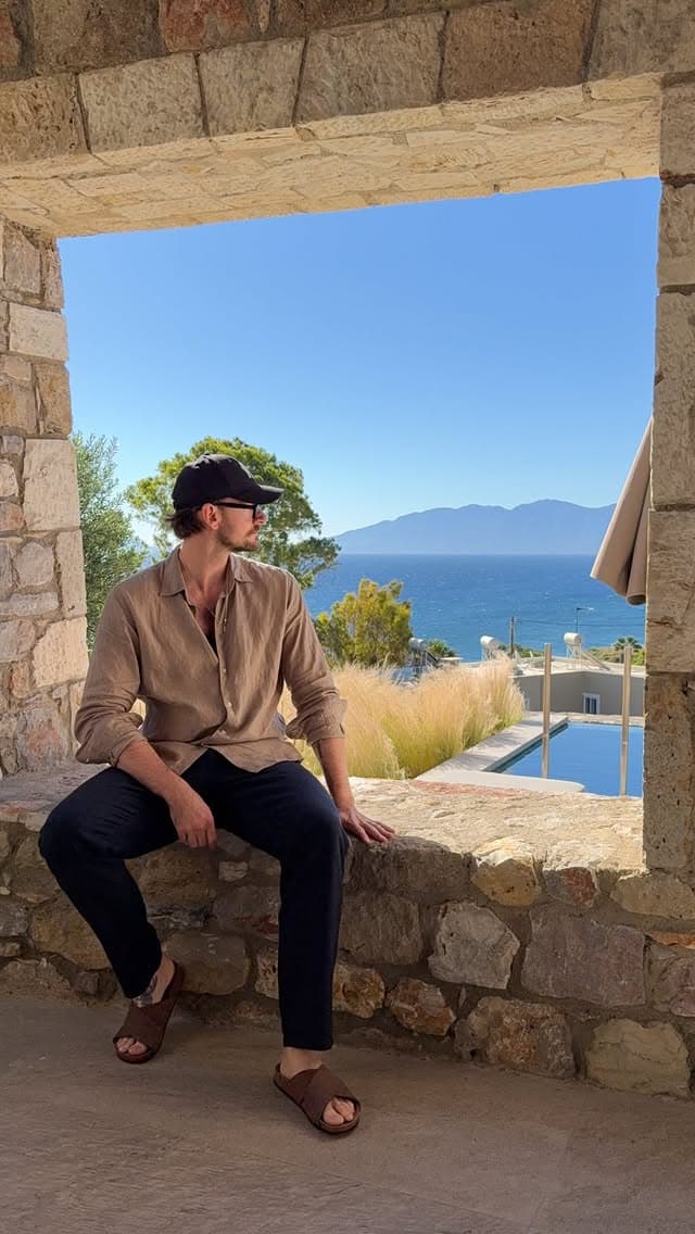 Marvin sitzt auf einer Steinmauer mit Blick aufs Meer