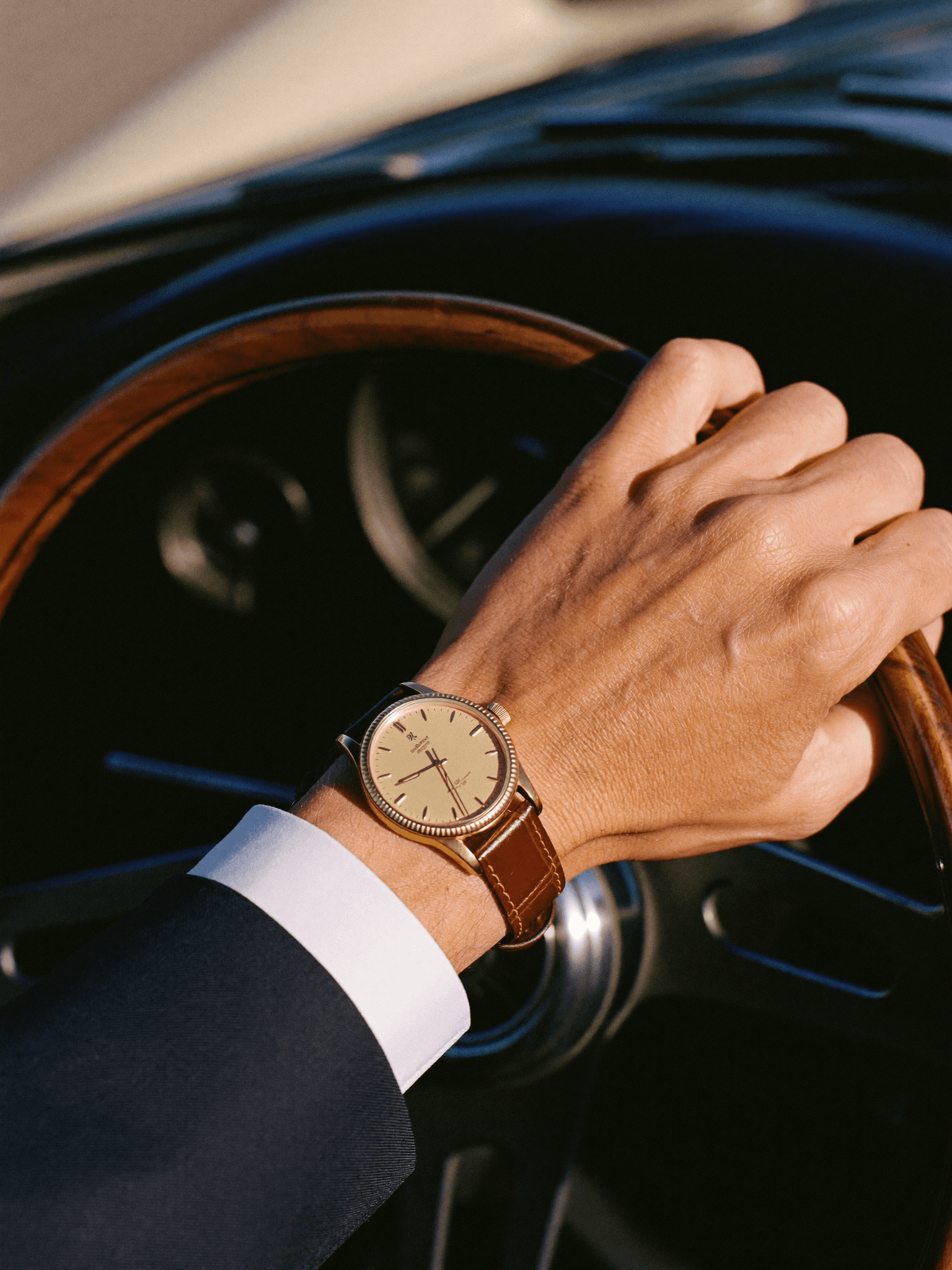 Goldene Uhr am Handgelenk auf dem Lenkrad eines Oldtimers